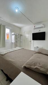 a bedroom with a large bed and a flat screen tv at Pousada Mar & Sol in Fortaleza