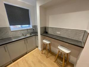 eine Küche mit zwei Hockern, einer Theke und einem Waschbecken in der Unterkunft Manvers house city centre in Nottingham