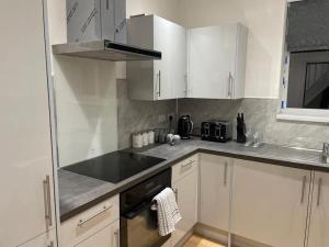 een keuken met witte kasten en een fornuis met oven bij Manvers house city centre in Nottingham