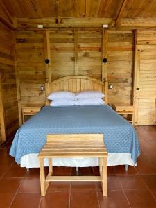 um quarto de madeira com uma cama e um banco em Hotel en Finca Chijul, reserva natural privada em San Juan Chamelco