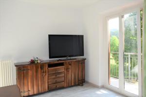 a flat screen tv sitting on top of a wooden dresser at Green House Mountain Lake Iseo Hospitality in Bossico