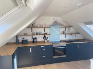 a kitchen with navy blue cabinets and a sink at Urgha Bay in Tarbert