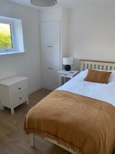 a white bedroom with a bed and a window at Urgha Bay in Tarbert