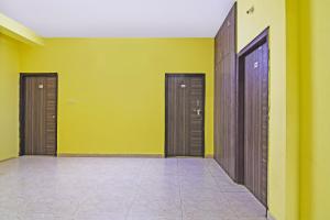 un couloir avec trois portes brunes et des murs jaunes dans l'établissement OYO Flagship Samrudhi Residency, à Jānla