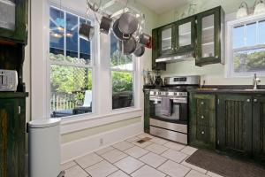 a kitchen with green cabinets and windows and a stove at Ville Villekulla! Private pool home near Historic Palmetto! in Palmetto