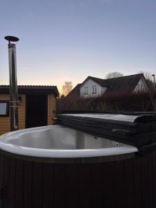 a bath tub with a faucet on a backyard at Charmerende stråtag strå hus (med Vildmarksbad) in Give