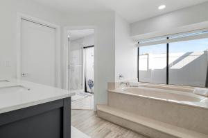 un bagno bianco con vasca e una grande finestra di Tropical Tranquility! Luxury pool home with lakefront view just minutes from the beach! a Bradenton