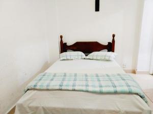 ein Bett mit zwei Kissen auf einem Zimmer in der Unterkunft Suíte Privativa com Ar Condicionado TV Frigobar 102 in Cabo Frio