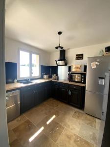 a kitchen with blue cabinets and a refrigerator and a window at Roxy House in Le Château-dʼOléron