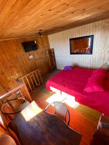 1 dormitorio con 1 cama roja en una cabaña de madera en Lilafken Apart Pichilemu, en Pichilemu