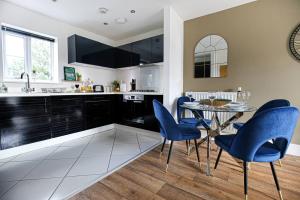 a kitchen with a dining table and blue chairs at Luxury Apartment with Balcony, Fast WIFI, Smart TVs and Free Parking by Yoko Property in Milton Keynes