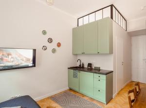 a kitchen with green cabinets and a tv on the wall at Apartament na Krakowskim Kazimierzu in Krakow