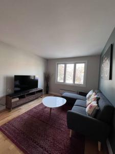 uma sala de estar com um sofá e uma mesa em Family-Friendly 3BR Home with Backyard em Montreal