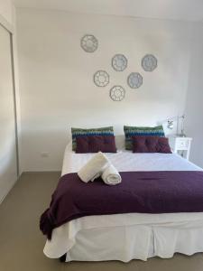 um quarto com uma cama grande e almofadas roxas em Rinconada del Mar em Punta del Este