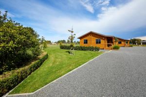 une maison avec une cour herbeuse à côté d'un bâtiment dans l'établissement Deerbrooke Kaikōura Chalets - Chalet 2, à Kaikoura