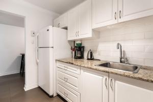 a white kitchen with a sink and a refrigerator at Grand appartement 4 chambres - 335 in Montreal