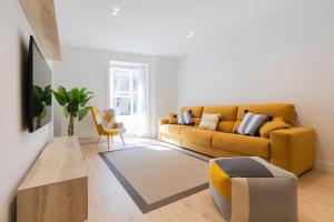een woonkamer met een gele bank en een stoel bij La cruz cozy apartment by Next Stop Bilbao in Bilbao