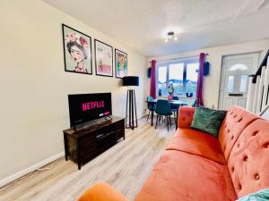 a living room with a orange couch and a television at Brand New! The Cosy Cove by Artisan Stays I Free Parking I Long Weekend Offer in Chelmsford