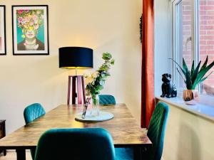 a dining room table with a vase of flowers on it at Brand New! The Cosy Cove by Artisan Stays I Free Parking I Sleeps 5 I Families or Contractors in Chelmsford