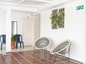 - deux chaises assises dans une pièce revêtue de carrelage dans l'établissement ALOJAMIENTO MOON, à Valledupar