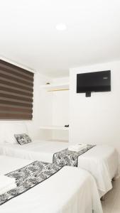 twee bedden in een kamer met een tv aan de muur bij ALOJAMIENTO MOON in Valledupar