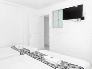 a white room with two beds and a flat screen tv at ALOJAMIENTO MOON in Valledupar