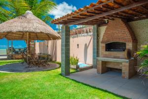 a patio with a brick fireplace and an umbrella at Casa de Praia, Paraíso de Tabuba! in Barra de Santo Antônio
