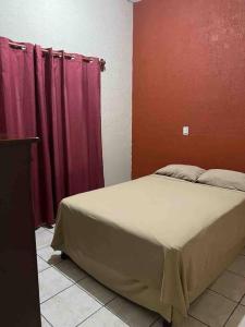 Cama en habitación con paredes rojas y cortinas moradas en Acogedor Depto 2 Rec. 1 Baño, Cocina Equip en Apatzingán de la Constitución