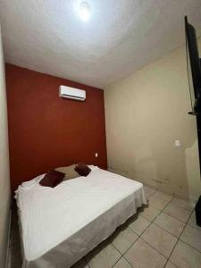 1 dormitorio con cama blanca y pared roja en Acogedor Depto 2 Rec. 1 Baño, Cocina Equip en Apatzingán de la Constitución