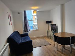 a living room with a blue couch and a table at Great Value Bath Street Ilkeston Apartment in Ilkeston
