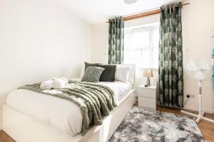 a white bedroom with a bed and a window at Cozy Family-Friendly House (3mins from Erith and Slade Green station) in Erith