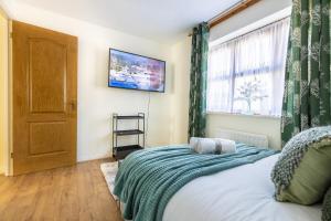 a bedroom with a bed and a television on the wall at Cozy Family-Friendly House (3mins from Erith and Slade Green station) in Erith