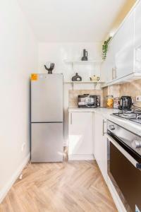 a kitchen with white cabinets and a refrigerator at Cozy Family-Friendly House (3mins from Erith and Slade Green station) in Erith