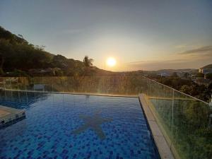 een groot zwembad met zonsondergang op de achtergrond bij Boho chic sea view apartment in Kata in Kata Beach