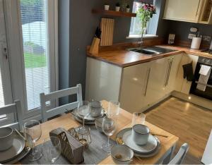 a kitchen with a wooden table with plates and wine glasses at The Westfield in Liversedge