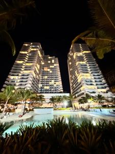twee hoge gebouwen naast een zwembad in de nacht bij LuxeBali Azure @ Azure North in San Fernando