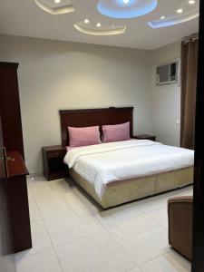 a bedroom with a large bed with pink pillows at ريحانة الهدا للوحدات السكنية in Al Hada