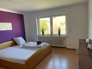 a bedroom with a bed and a purple wall at Red Dot Apartments in Kamen