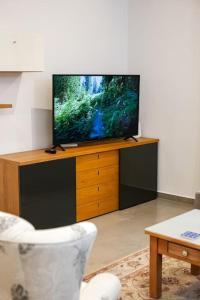 telewizor z płaskim ekranem siedzący na szczycie drewnianego centrum rozrywki w obiekcie Lovely 3 bed - Apartment -Sliema w mieście Sliema