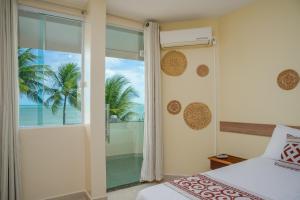 a bedroom with a view of the ocean from a window at Paraíso de Tabuba - casa de aluguel por temporada - 32km de Maceió-AL - Pé na areia - 24h de Frente para o mar in Barra de Santo Antônio +101 photos