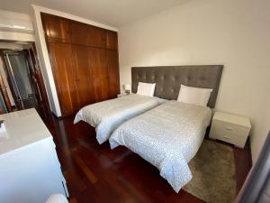 a bedroom with two beds and a wooden headboard at Santa Luzia Apartment in Funchal