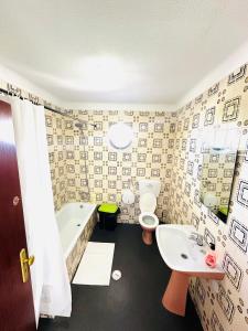 La salle de bains est pourvue d'une baignoire, d'un lavabo et de toilettes. dans l'établissement Portimao Central Holiday Guesthouse, à Portimão