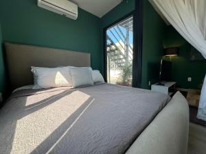 a bedroom with a large bed with green walls and a window at Casa Arsha Beachfront Paradise in Santa Clara