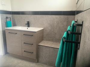 a bathroom with a sink and green towels at The Corner Cottage Orbost in Orbost