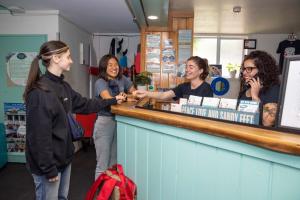 a group of women standing around a counter at Pacific Coast Lodge and Backpackers in Mount Maunganui