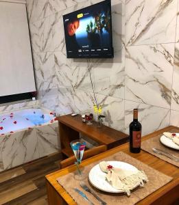 Chales Maria Flor في جونسالفيس: طاولة مع صحن وزجاجة من النبيذ