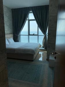 a bedroom with a bed and a large window at Sunset Beach View Holiday Homes in Ajman 