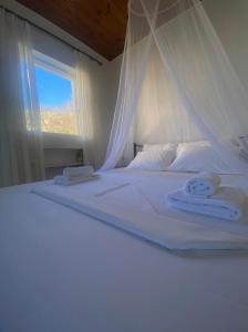 Una cama blanca con dos toallas y una ventana. en Camarina Sea View en Kamarína