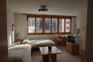 Zimmer mit 2 Betten, einem Tisch und einem TV in der Unterkunft The Window to the Mountains in Arosa