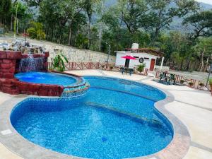 a swimming pool with a water fountain in a yard at Hotel Hacienda Huasteca in Aquismón